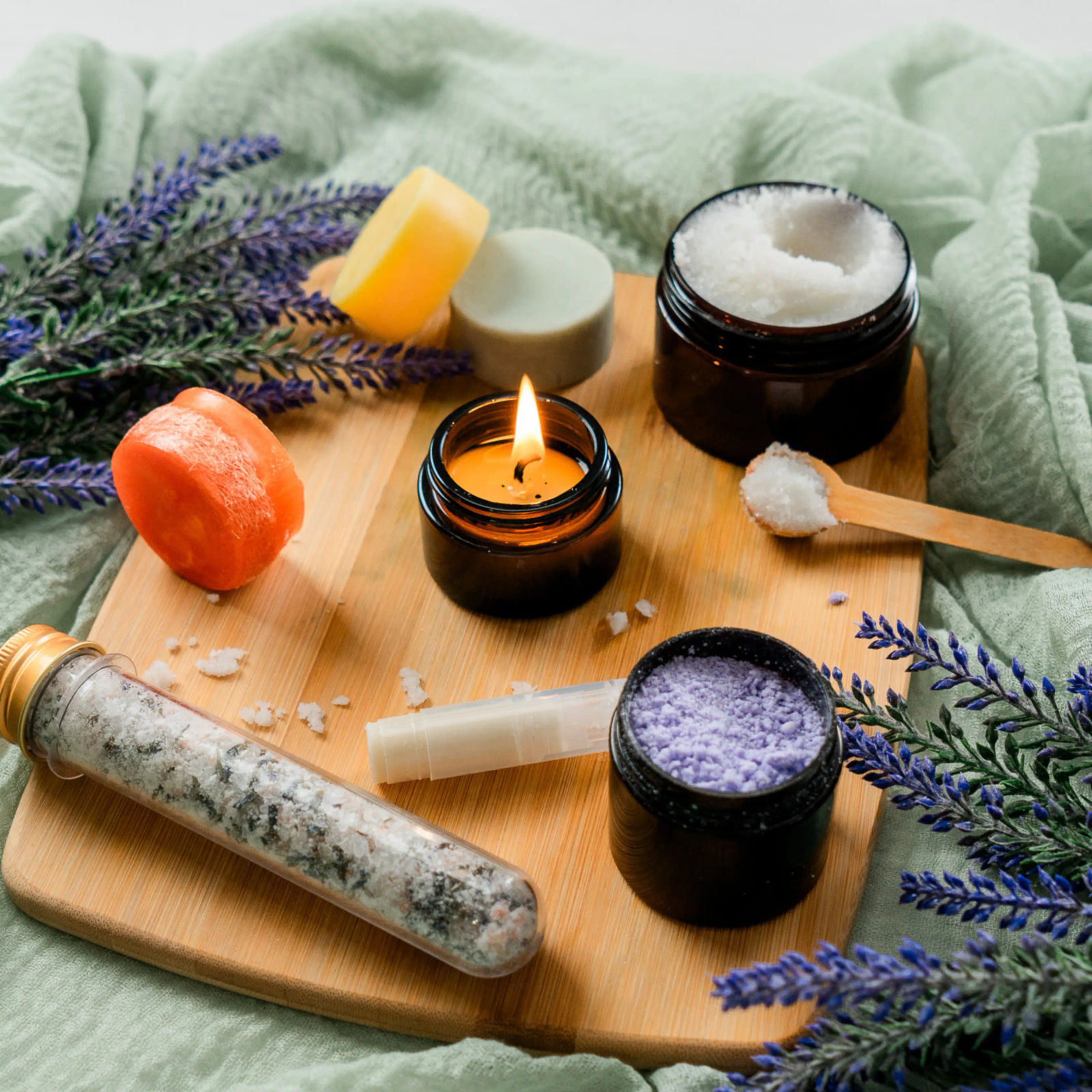 Homemade gifts on a wooden board: a candle, sugar scrub, bath salts and soap