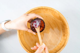 Homemade rose foot soak tipped from an amber jar into a wooden bowl