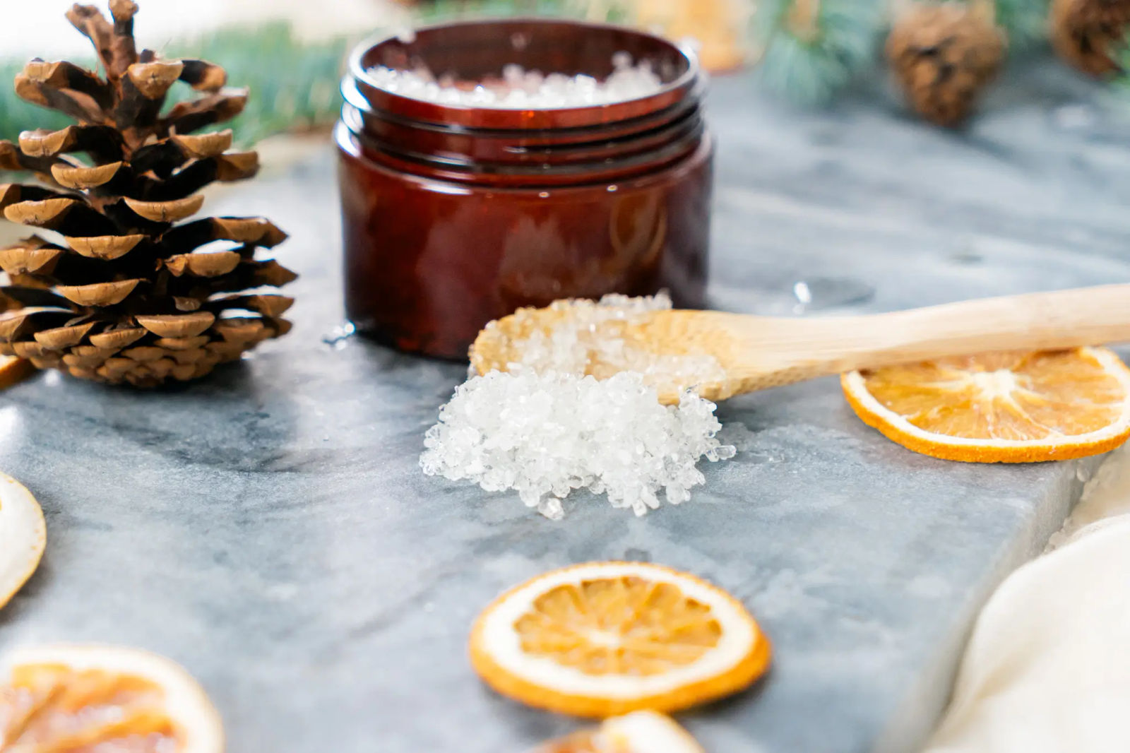 A jar of homemade Muscle Mend bath soak with a wooden scoop