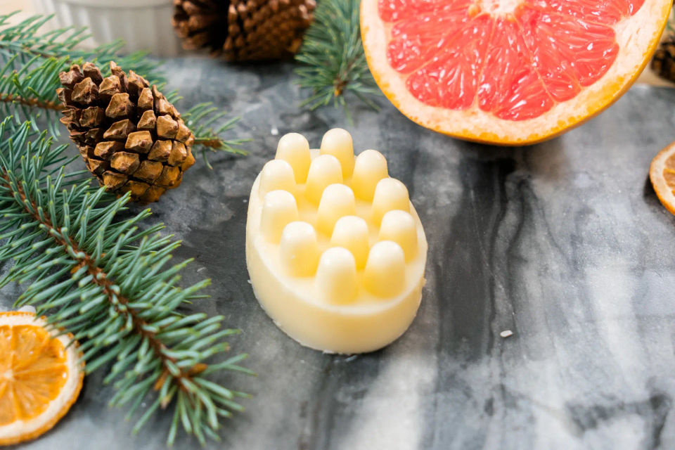 A homemade Wildwood wellness bar with massage knobs, beside grapefruit and pine
