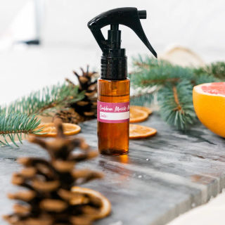 An amber spray bottle of homemade Cooldown muscle mist among pine and grapefruit