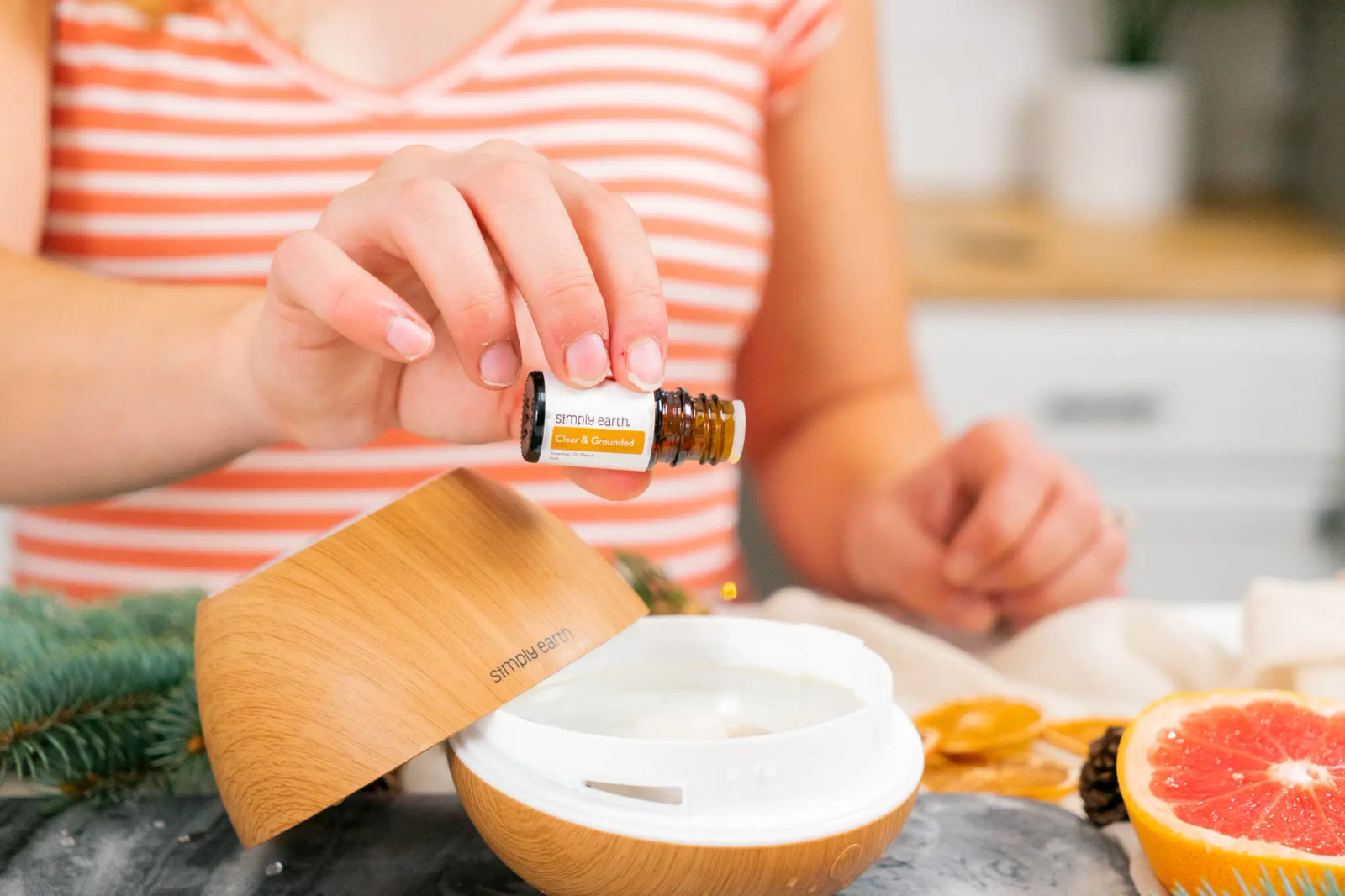 Clear & Grounded diffuser blend dropped from its bottle into a wooden diffuser