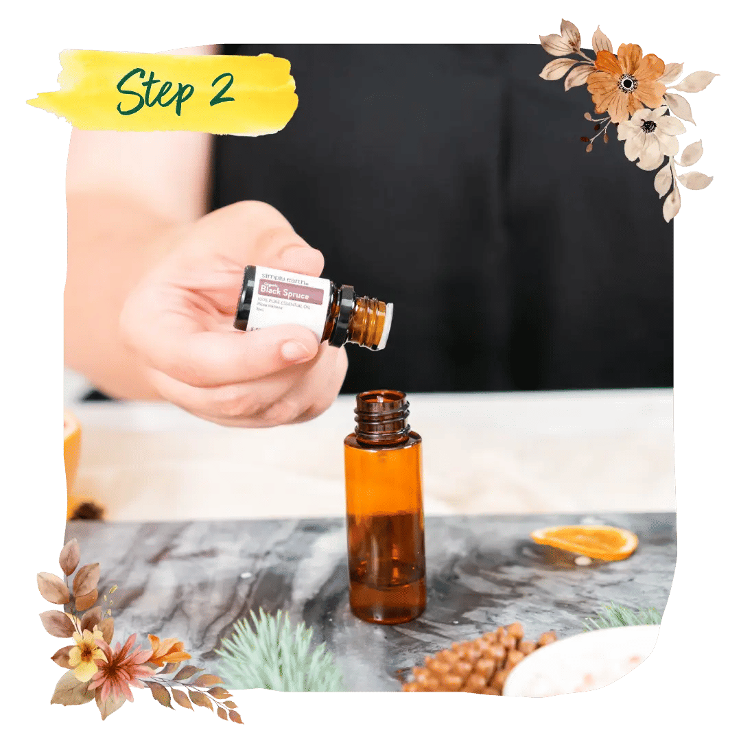 Step 2 &mdash; a maker dripping essential oil into a glass bowl among pine and dried orange